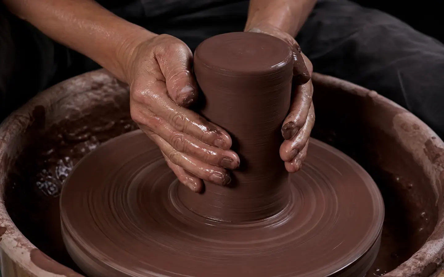 Artisan raising wet Jianshui clay on a pottery wheel