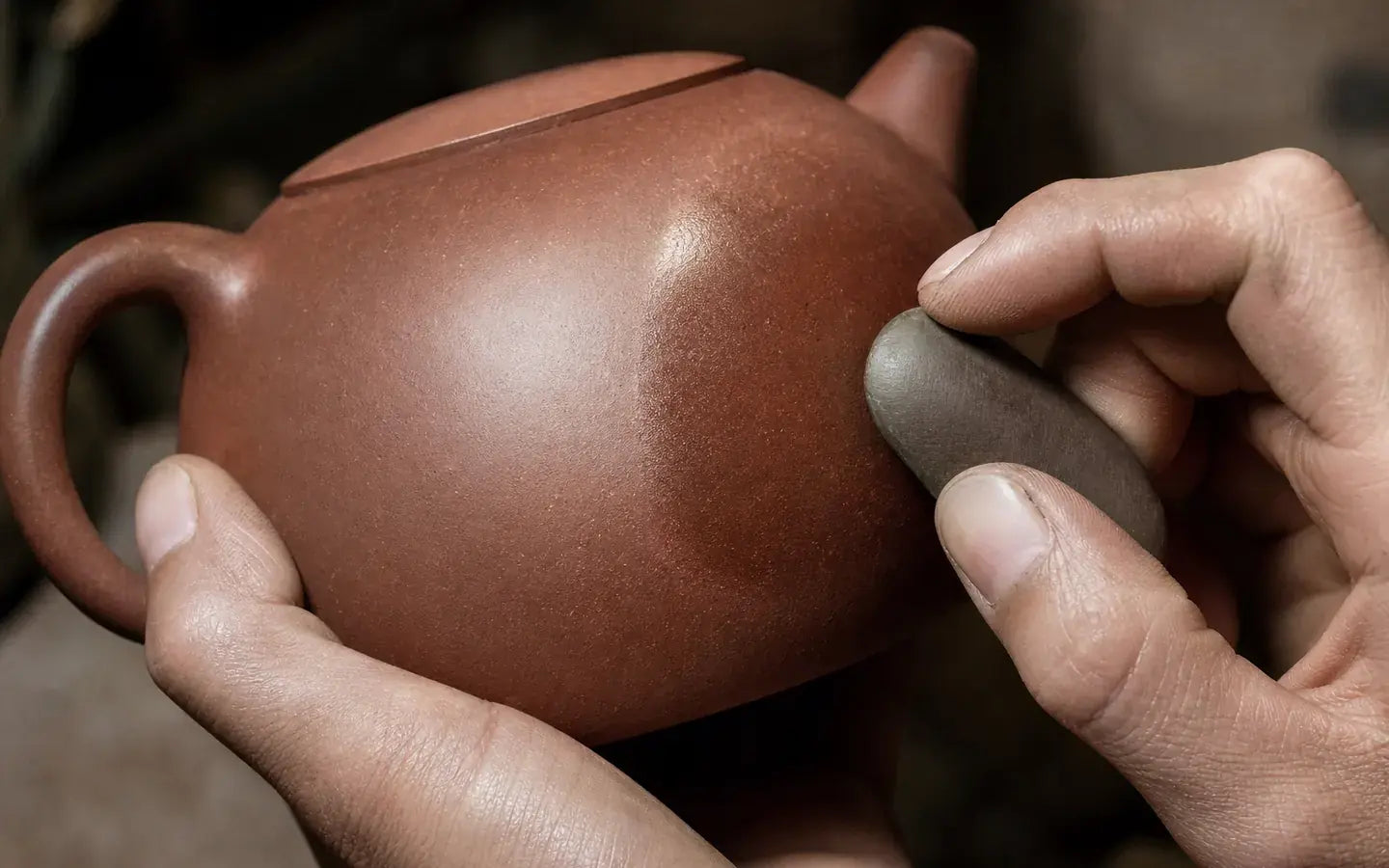 Unglazed Jianshui teapot being polished with a smooth stone